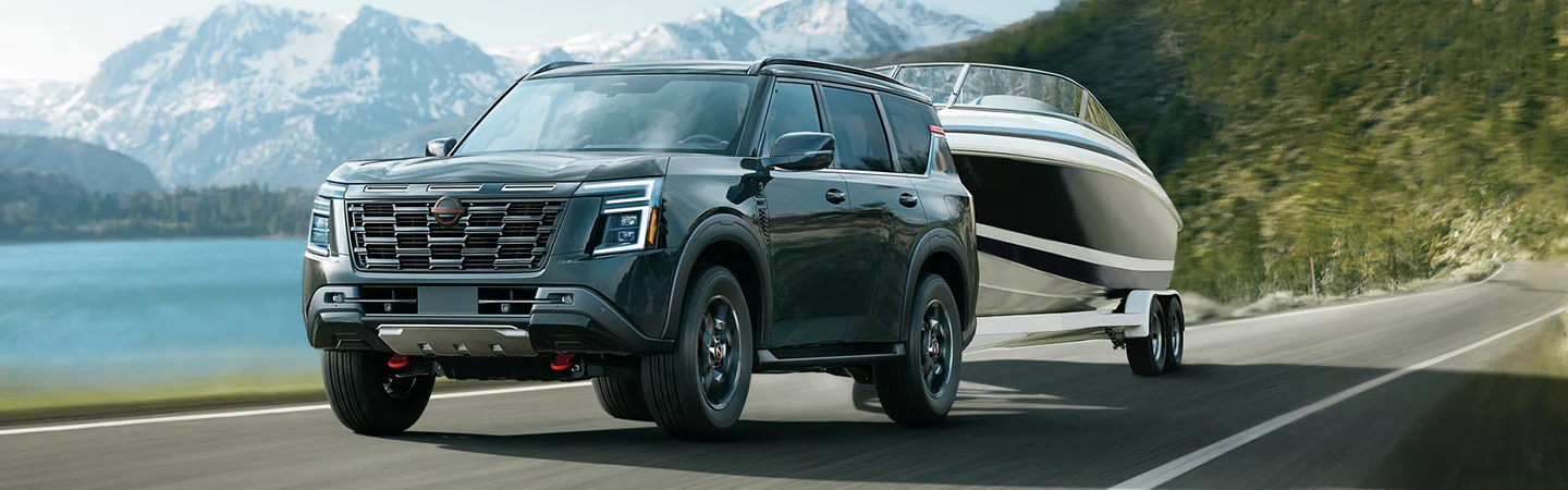 2025 Nissan Armada towing a boat on a country road