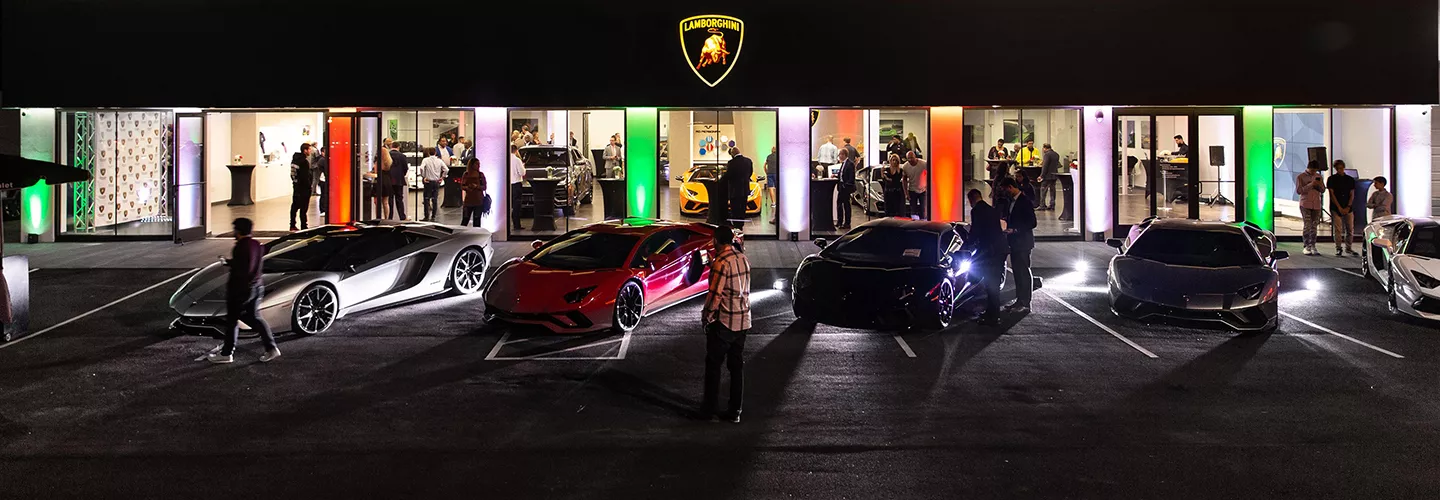 Lineup of Lamborghini Huracan Tecnica cars in a parking lot in front of a Lamborghini dealership