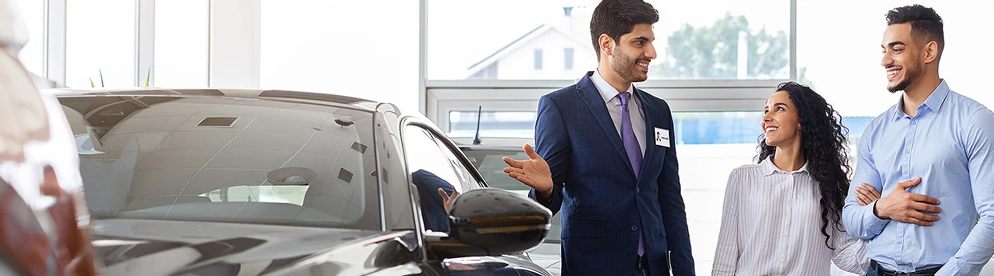 Sales person helping out customers look at new cars