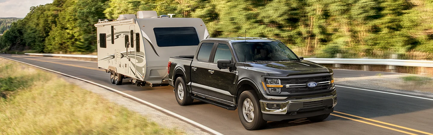 A 2025 Ford F-250 towing a camper on a road