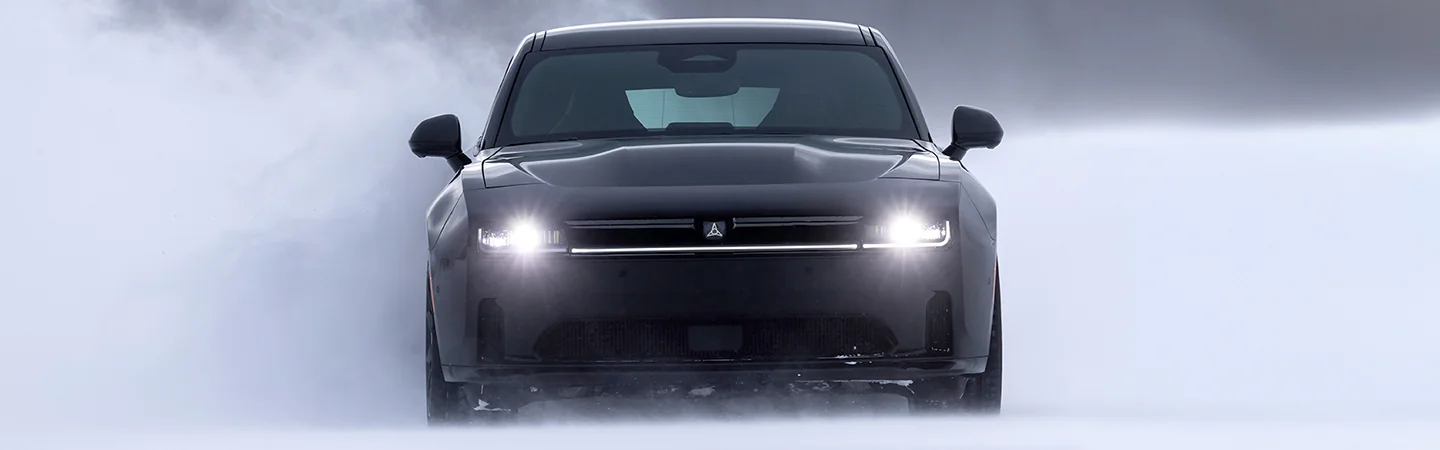 Front view of a black 2025 Dodge Charger drinvg in the snow