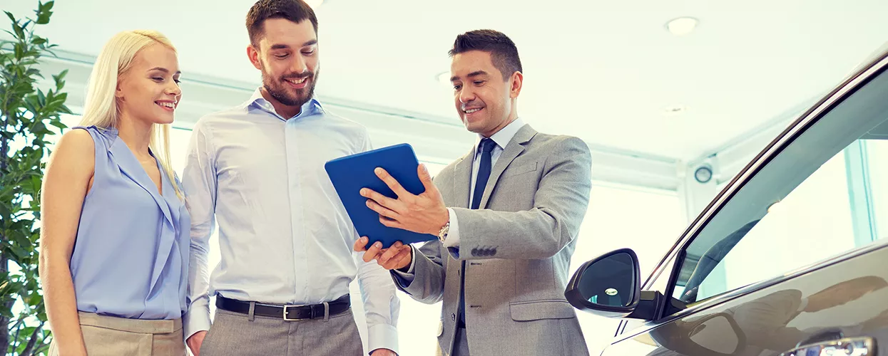 Car salesman talking to a couple in a car dealership