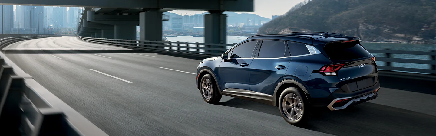 Back side view of a blue 2025 Kia Sportage Hybrid on highway