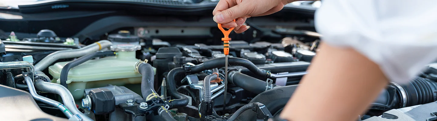 auto mechanic checking oil on car pulling up dipstick