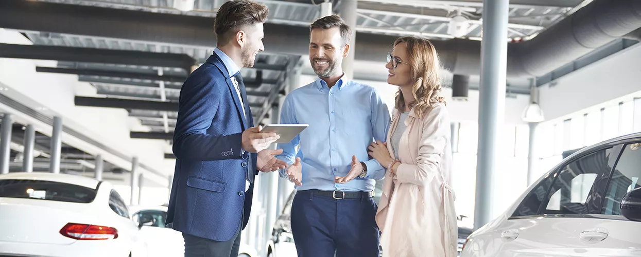 Car salesman talking to a couple in a car dealership
