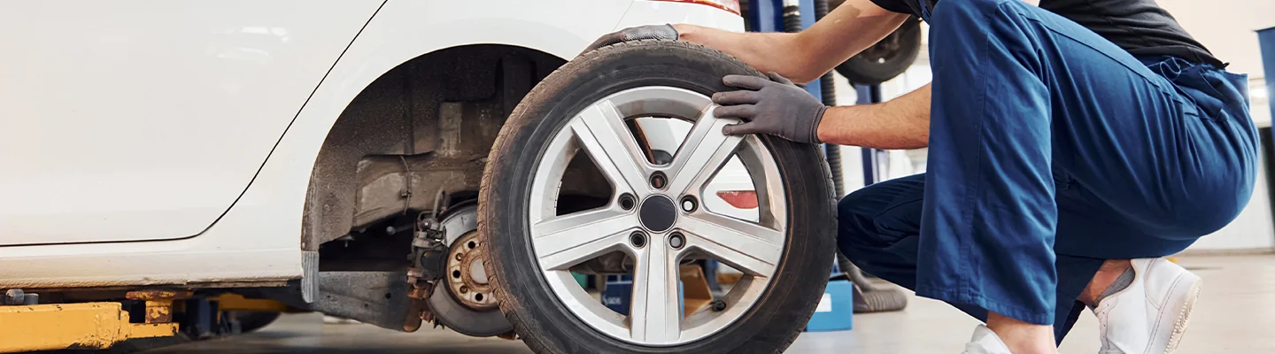 auto mechanic wotking with tires by car in shop