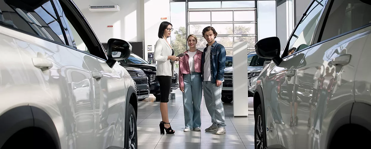 Blog Post in Customers speaking with a dealership sales representative while shopping for new SUVs inside a modern automotive showroom