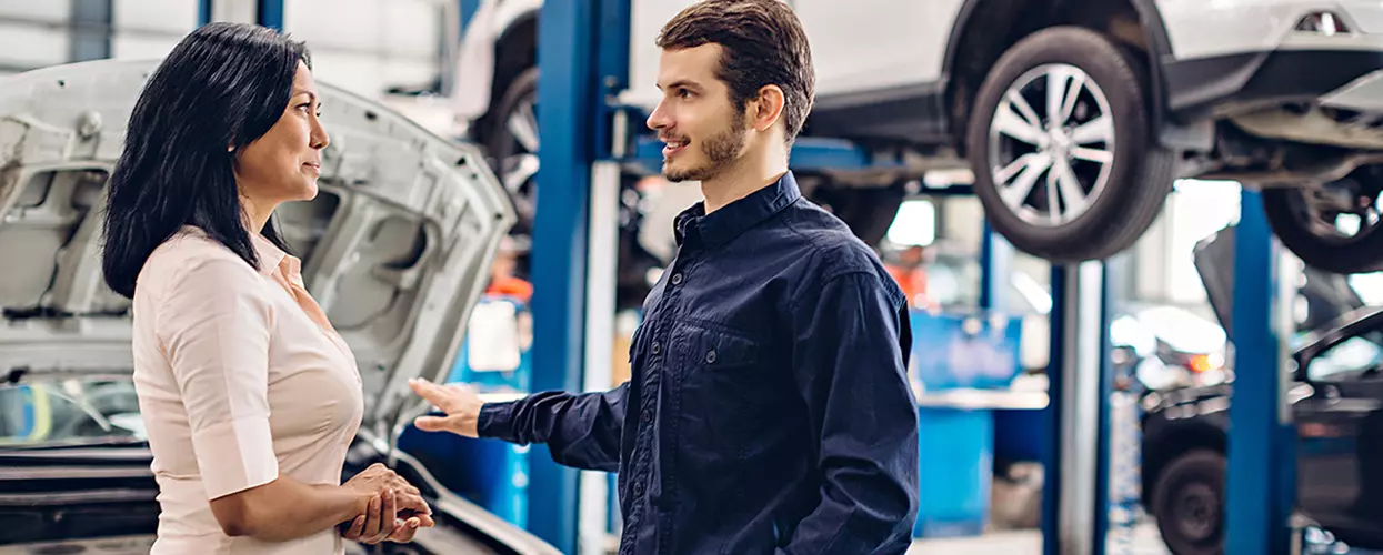 Service advisor explaining vehicle maintenance recommendations to a customer in a professional automotive service center