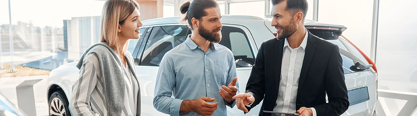 couple speaking with car salesperson about financing vs leasing