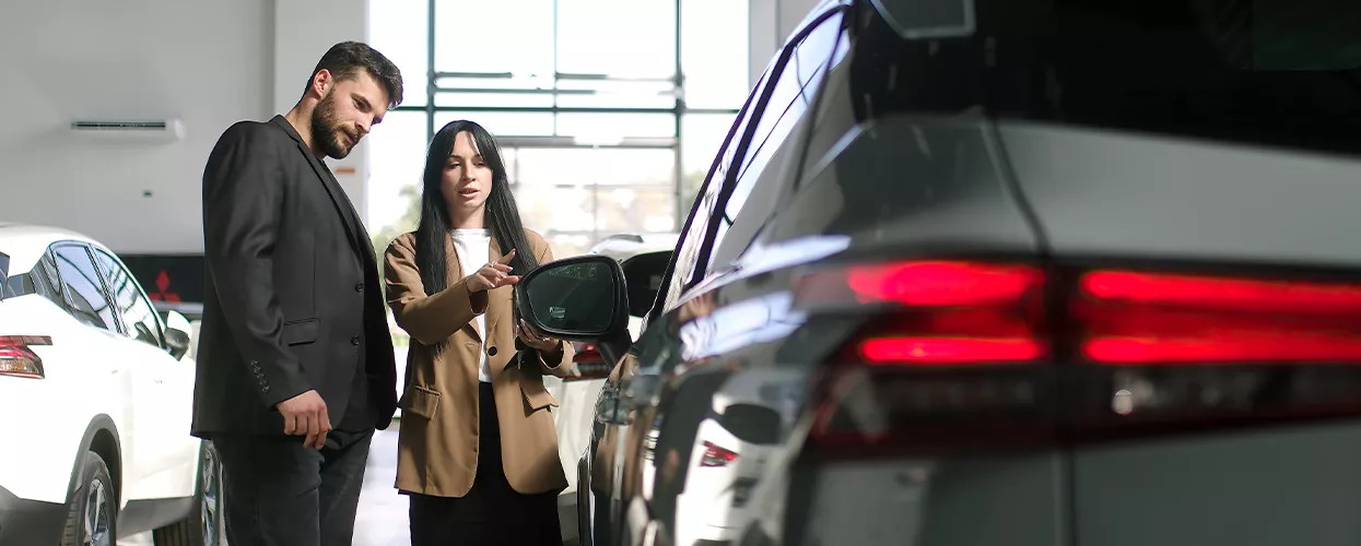 Car sales woman showing a customer a new car