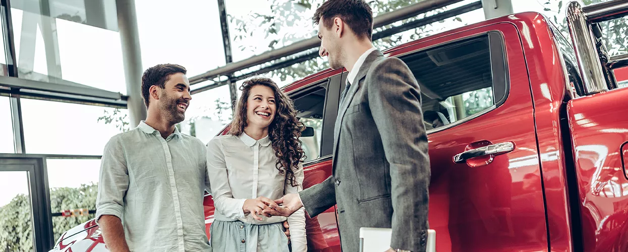 Car saleswoman handing a new set of car keys to a couple