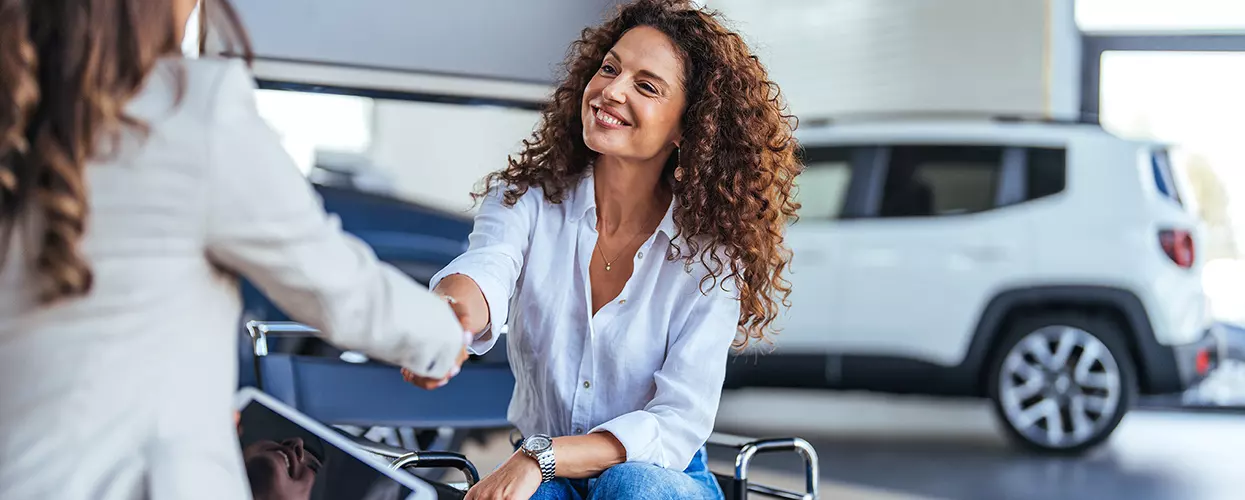Blog Post in Customer shaking hands with a dealership representative after purchasing a vehicle inside a modern automotive showroom