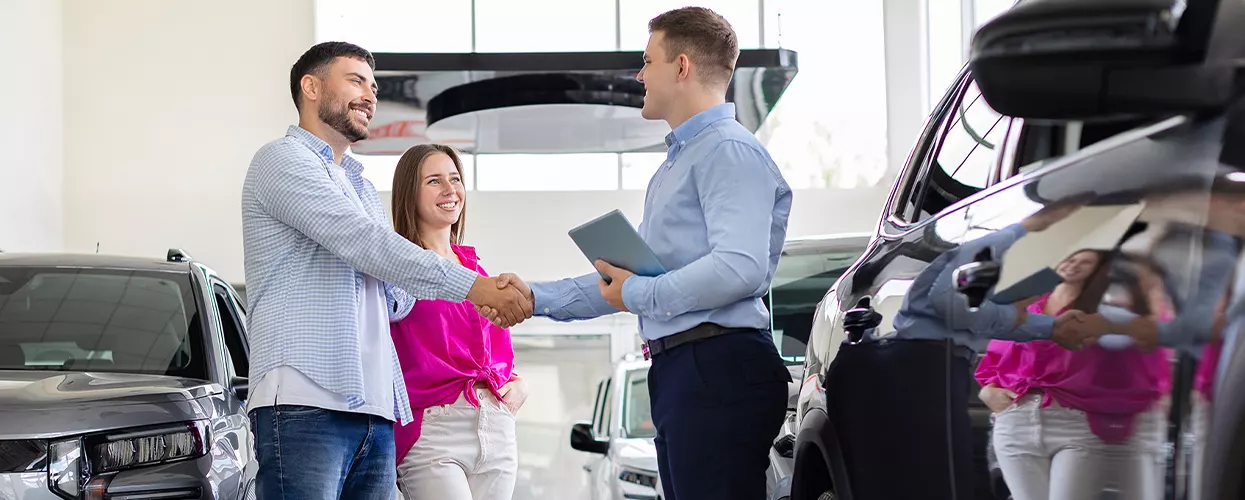 Car salesman showing a couple a new vehicle