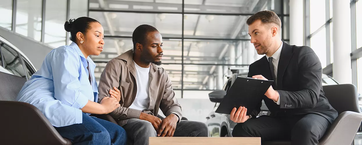 a couple speaking with car salesperson going over details of INEOS Grenadier Fieldmaster model at a dealership