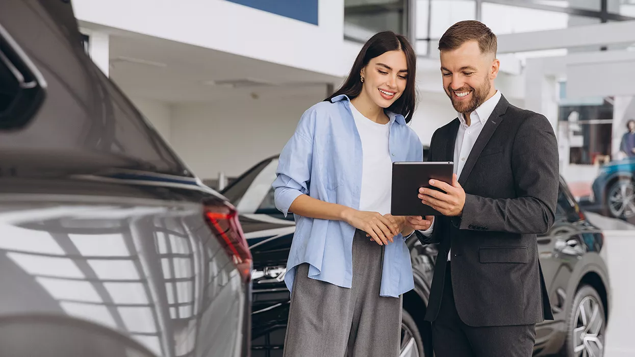 Car salesman and woman looking at a document in a car dealership