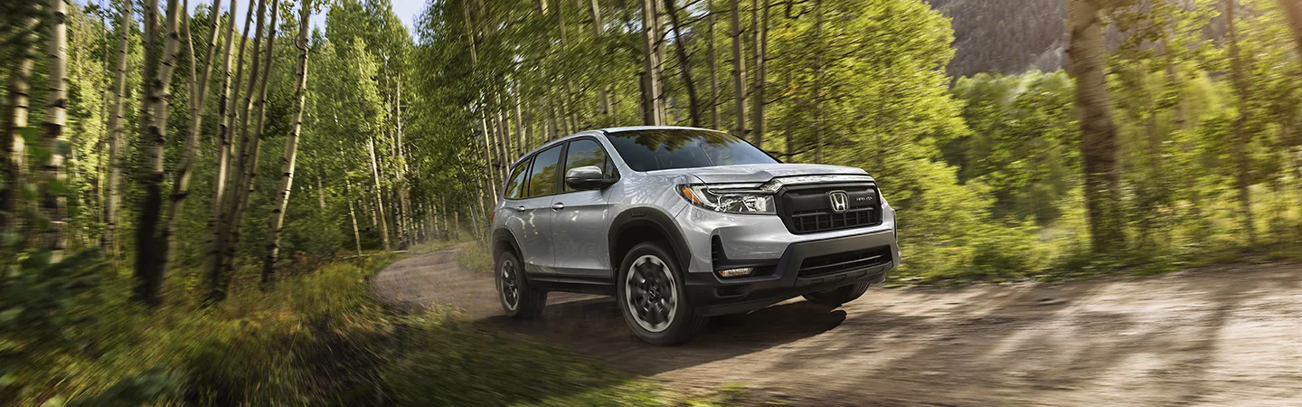 Gray 2025 Honda Passport driving in the woods