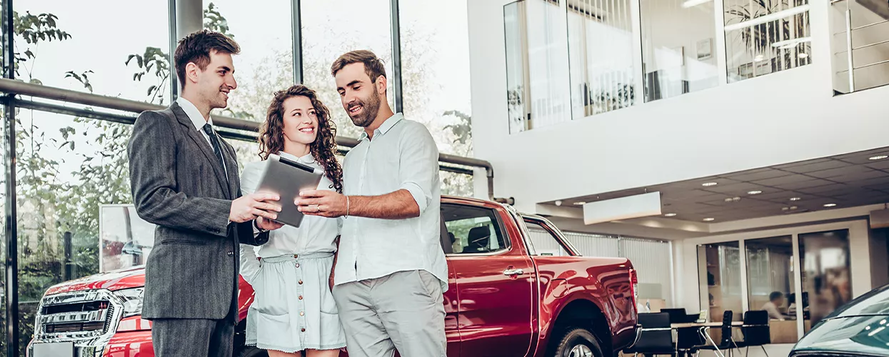 Car salesman showing a couple a new car in a dealership