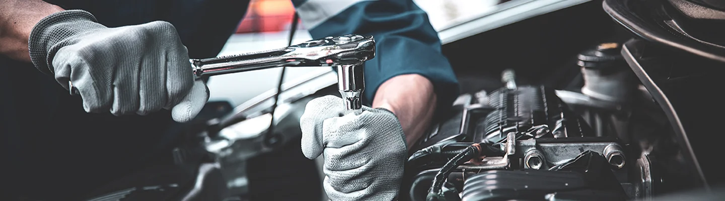auto mechanic with socket wrench working on car