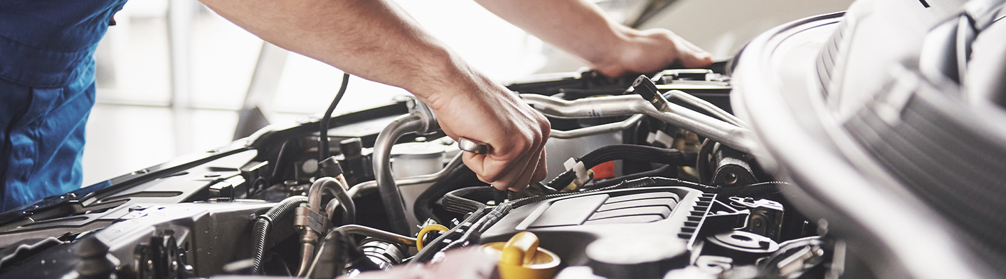 Close up view of a technician working on a car’s engine