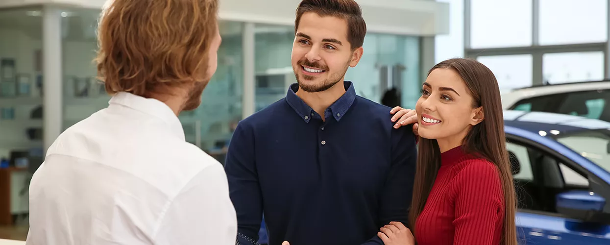 A couple talking to a car salesman in a dealership