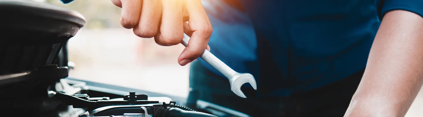 car mechanic holding a wrench working on car