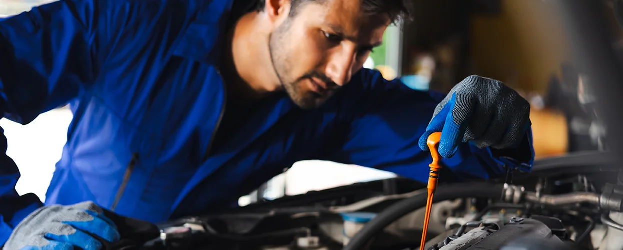 auto mechanic workng on car leaning into engine compartment