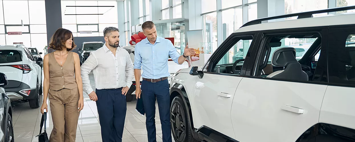 Car salesman showing a couple a new vehicle