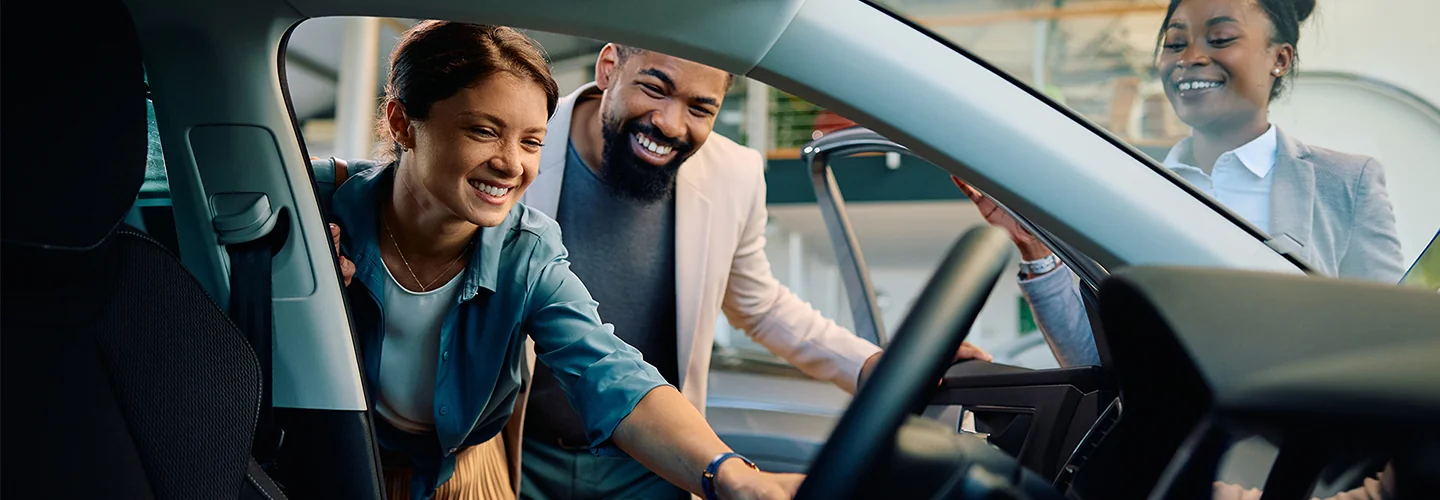 Sales person showing a couple the inside of a Used SUV