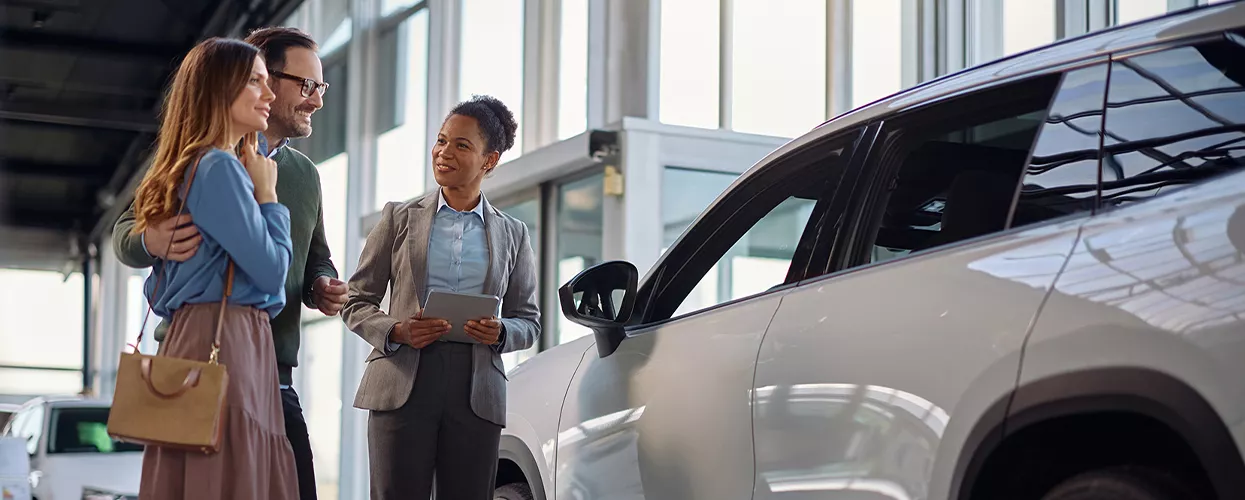 Car salesman showing a couple a new vehicle
