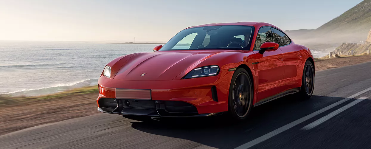 red Porsche Taycan driving on coastal road