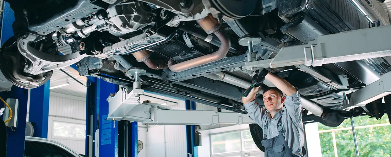 Service Mechanic working on a car lifted in the air