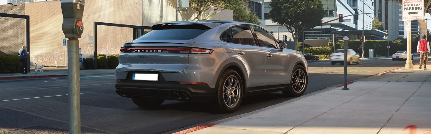 Rear view of a gray 2025 Porsche Cayenne driving on a city street
