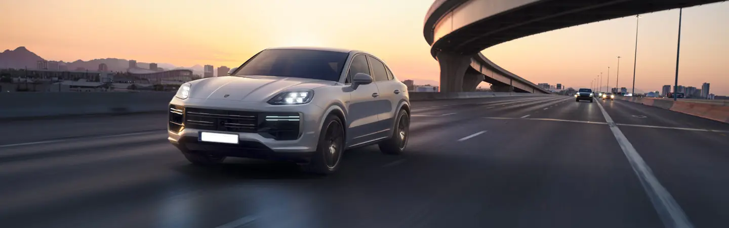 Front view of a gray 2025 Porsche Cayenne driving on a freeway