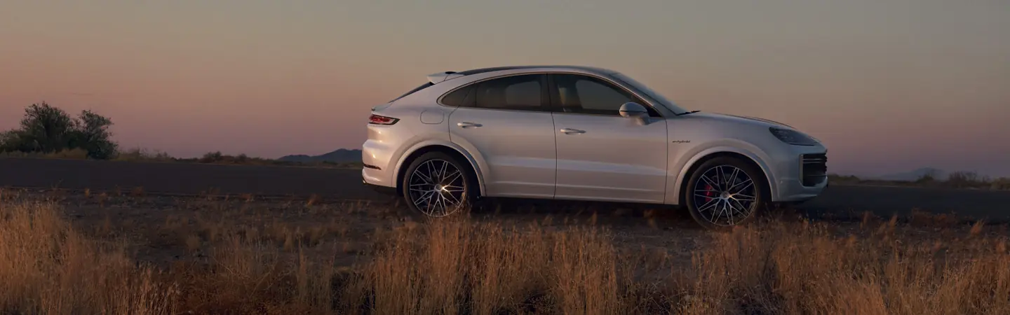 Side view of a gray 2025 Porsche Cayenne parked in a field