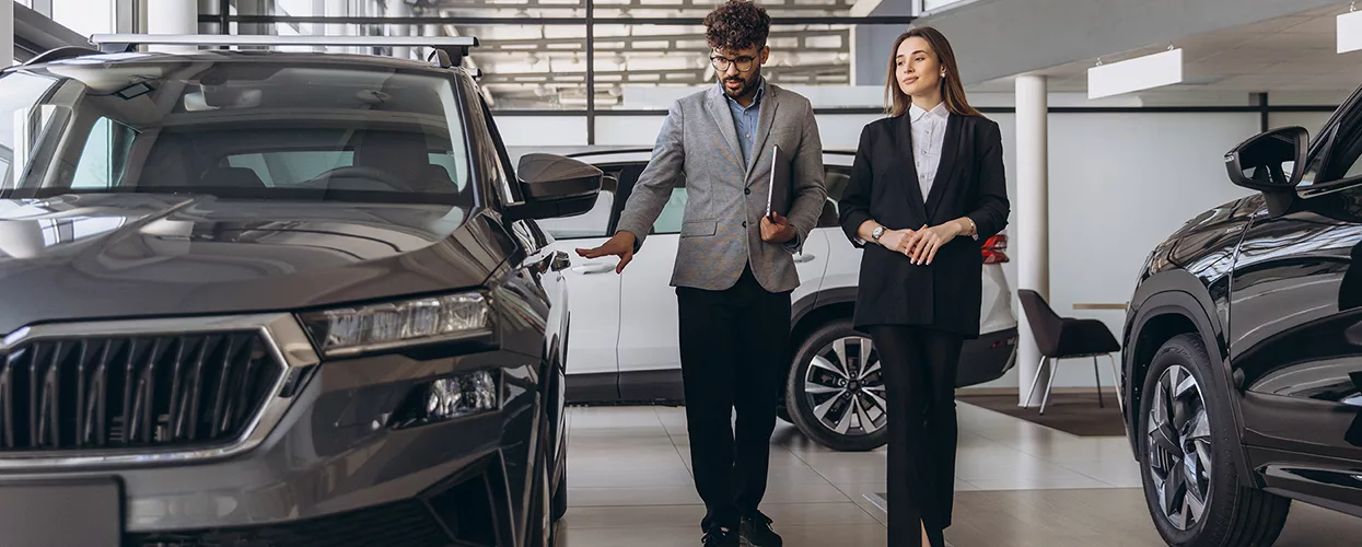 two people walking in the dealership showroom talking bout a Mazda SUV