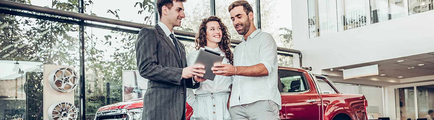 couple speaking with car salesperson about financing vs leasing