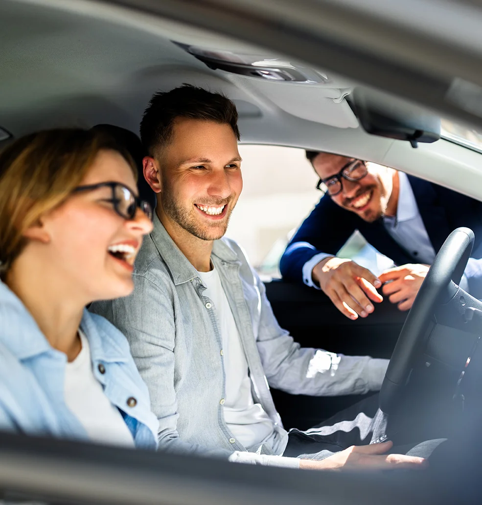A man and woman are seated in a car, sharing a laugh and a moment of happiness.