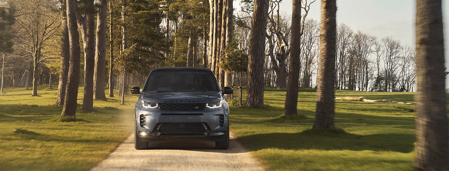 front view of a 2025 Discovery Sport driving on a tree lined driveway