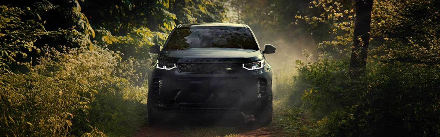 front view of a 2025 Discovery Sport S driving through the woods on dirt road