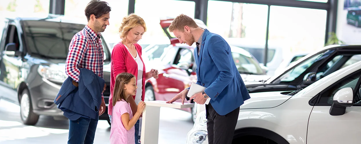 Sales person talking to a family about cars