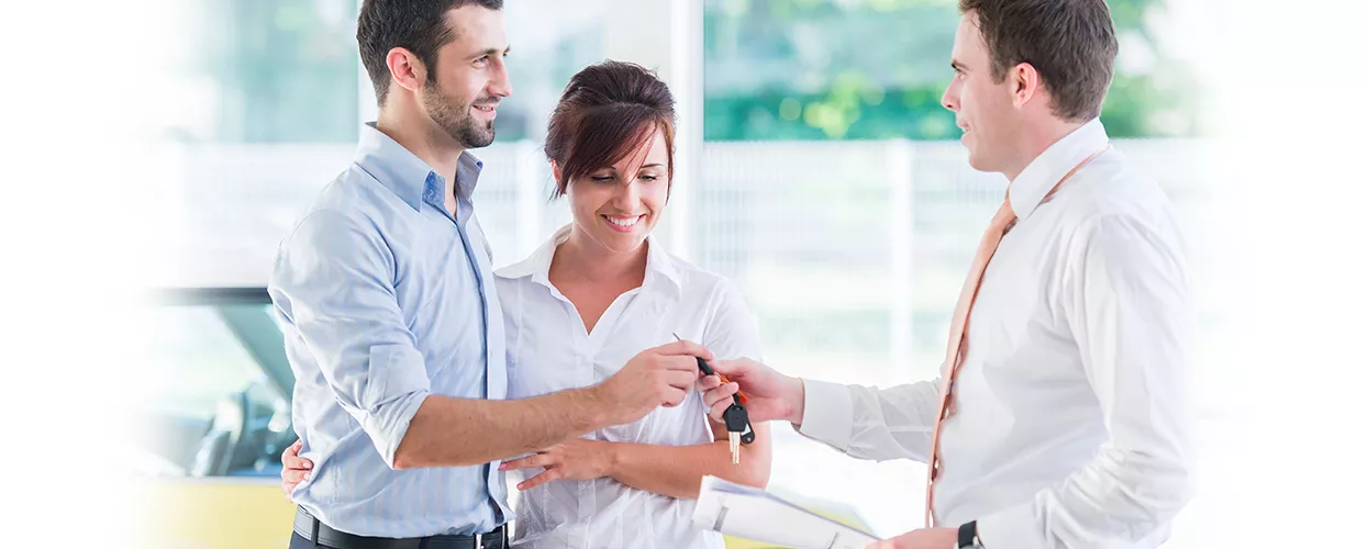 Car salesman handing a new set of car keys to a couple