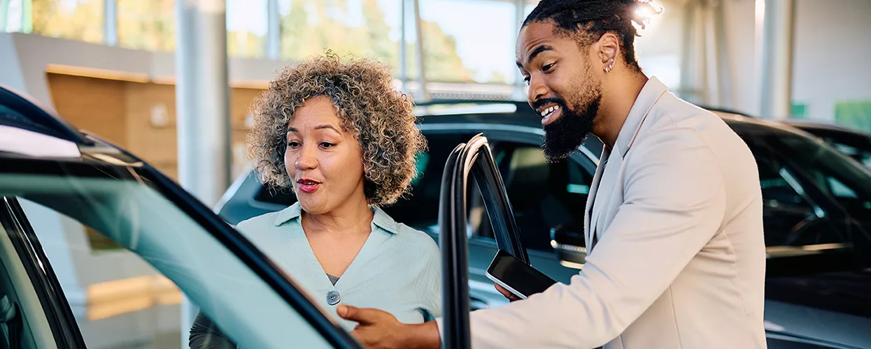 Car salesman showing a woman a new vehicle at a car dealership