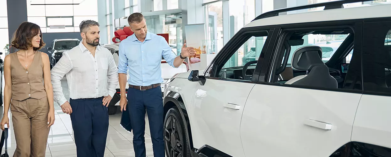 Car salesman showing a couple a new vehicle