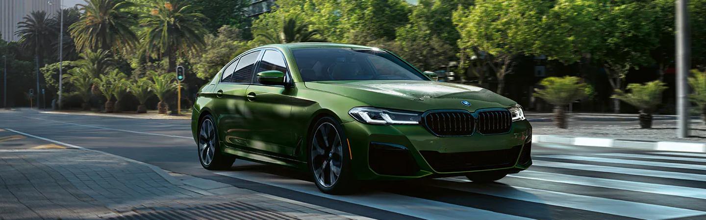 Green 2022 BMW 5 Series driving in the city
