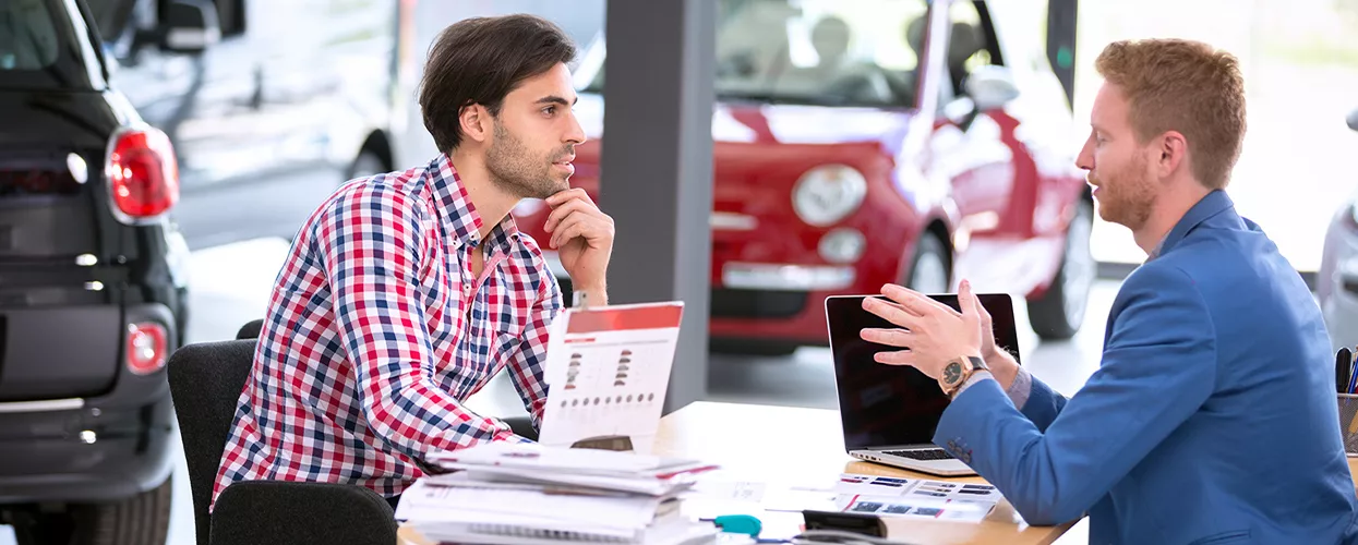 Car salesman talking to a customer in a car dealership