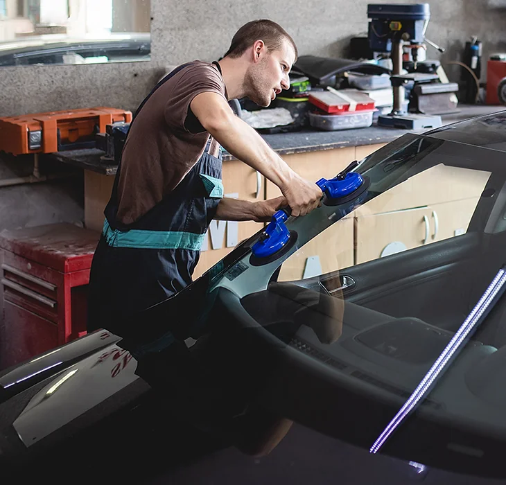 mechanic in the shop working on windshield of a vehicle