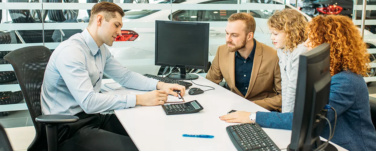 Car salesman talking a family through a contract at a dealership