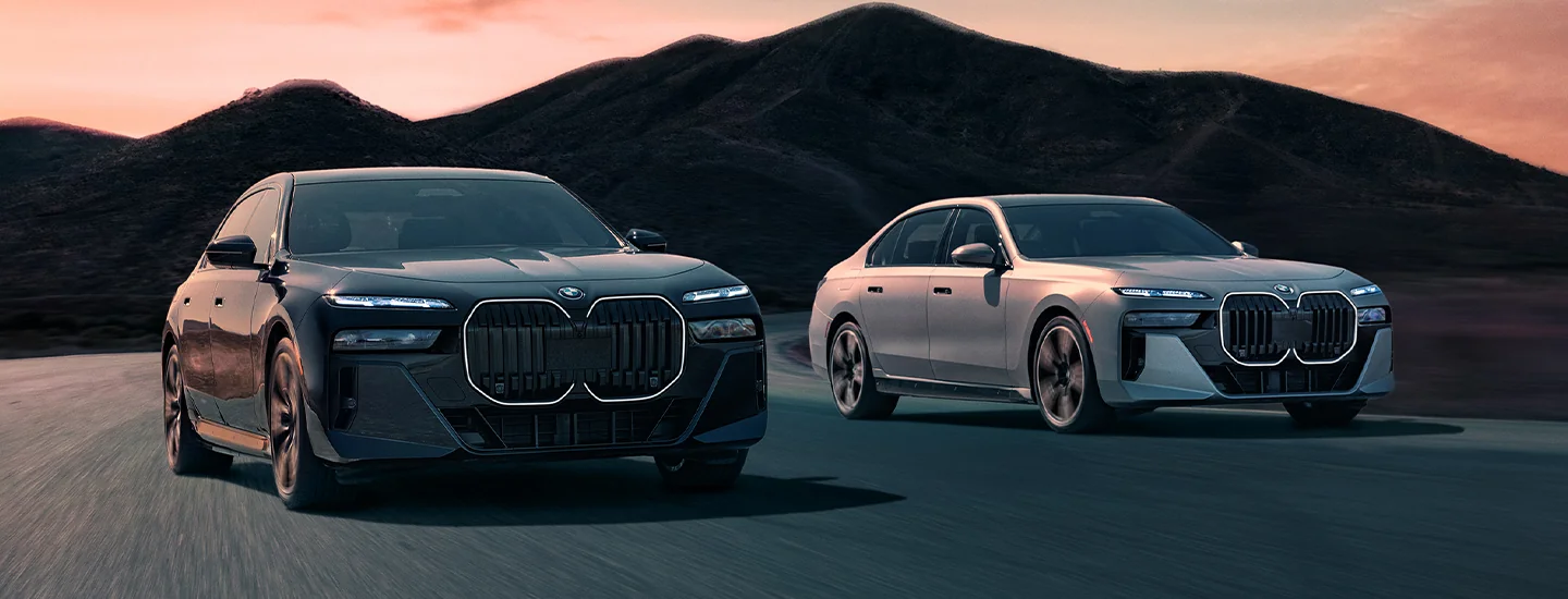 2 BMW a 2025 BMW i7 eDrive50 and M70 lineup parked at sunset at foothills of mountains