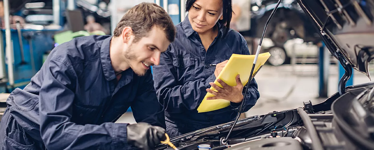 Two service mechaincs working under the hood of a vehicle