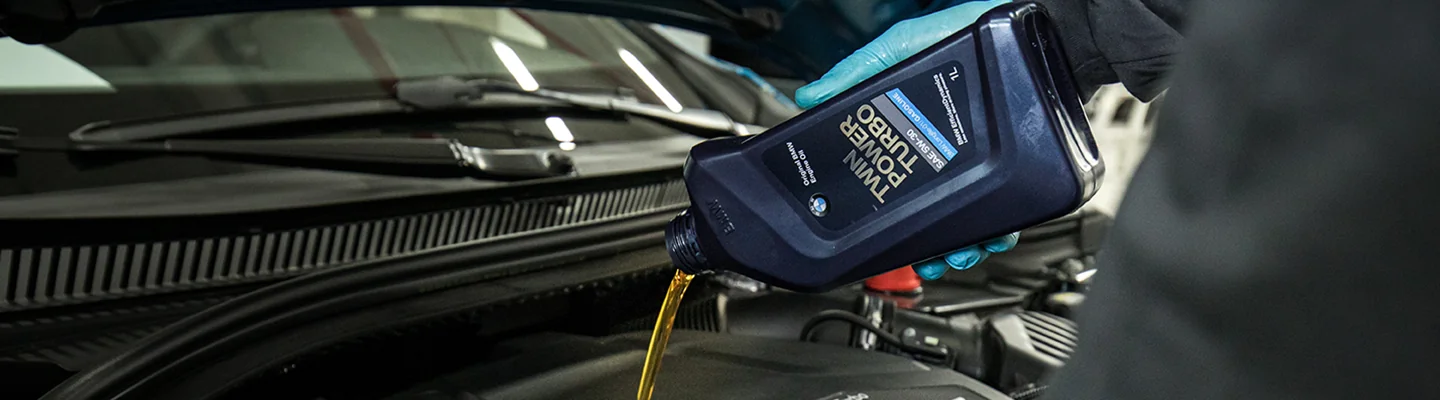 Mechanic putting oil in a BMW vehicle